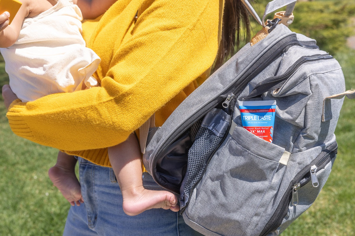 Mom holding baby and diaper bag with Triple Paste® 3XMax in it.