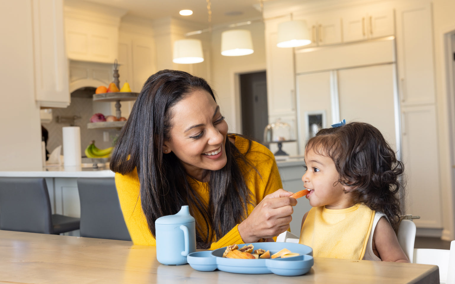 Mother feeding toddler carrot sticks